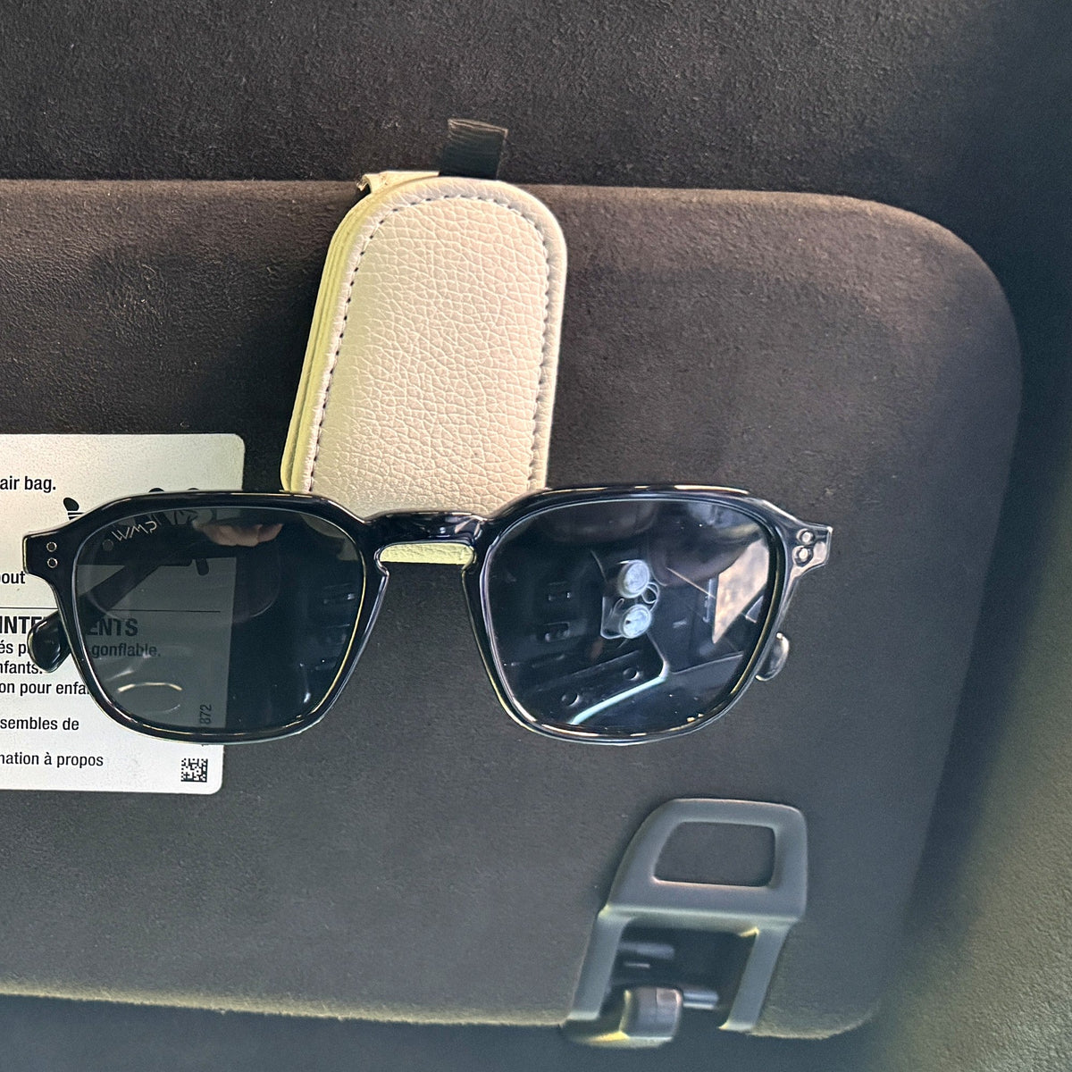 Tossits sunglasses clip holding sunglasses on a car visor